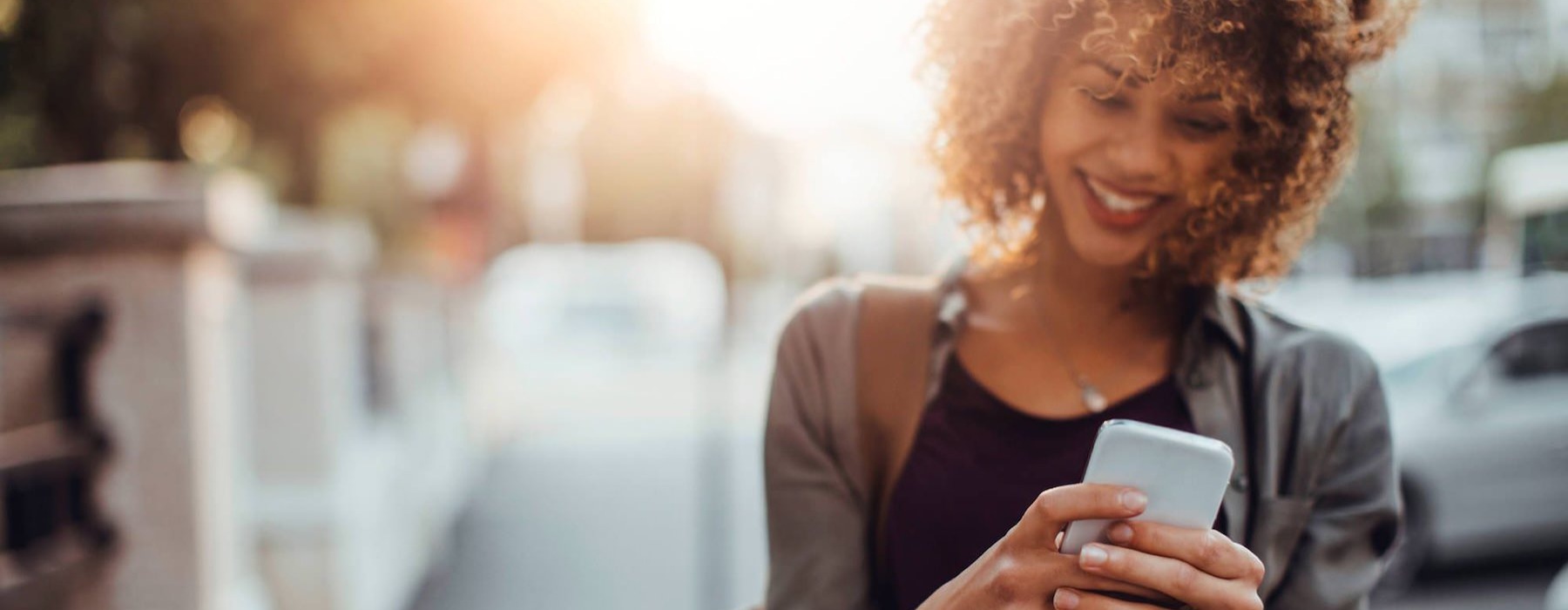 woman texts on her phone as she walks through the city